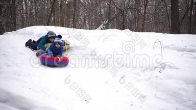 两个孩子坐在雪山上的雪橇上。孩子们用雪橇摔倒。体育和户外活动